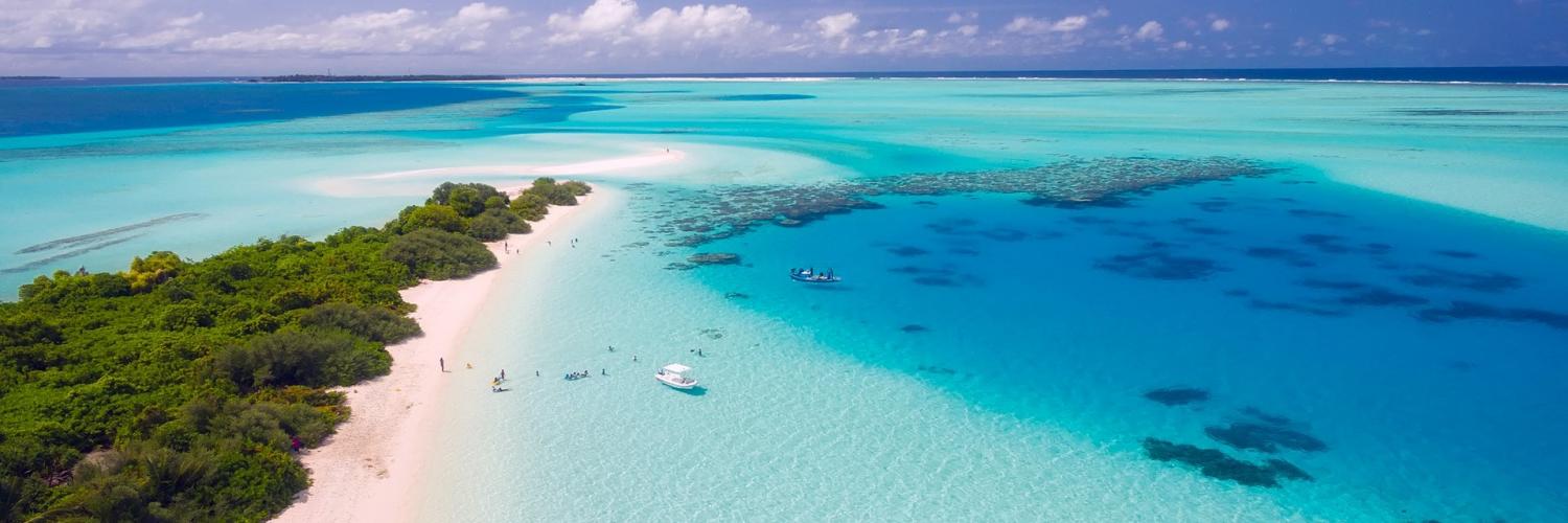 A blue, tropical ocean with a beach to the left