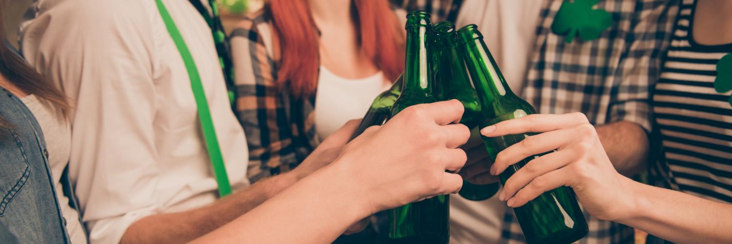 A group of young people dressed up for St. Patrick's Day, clinking beers