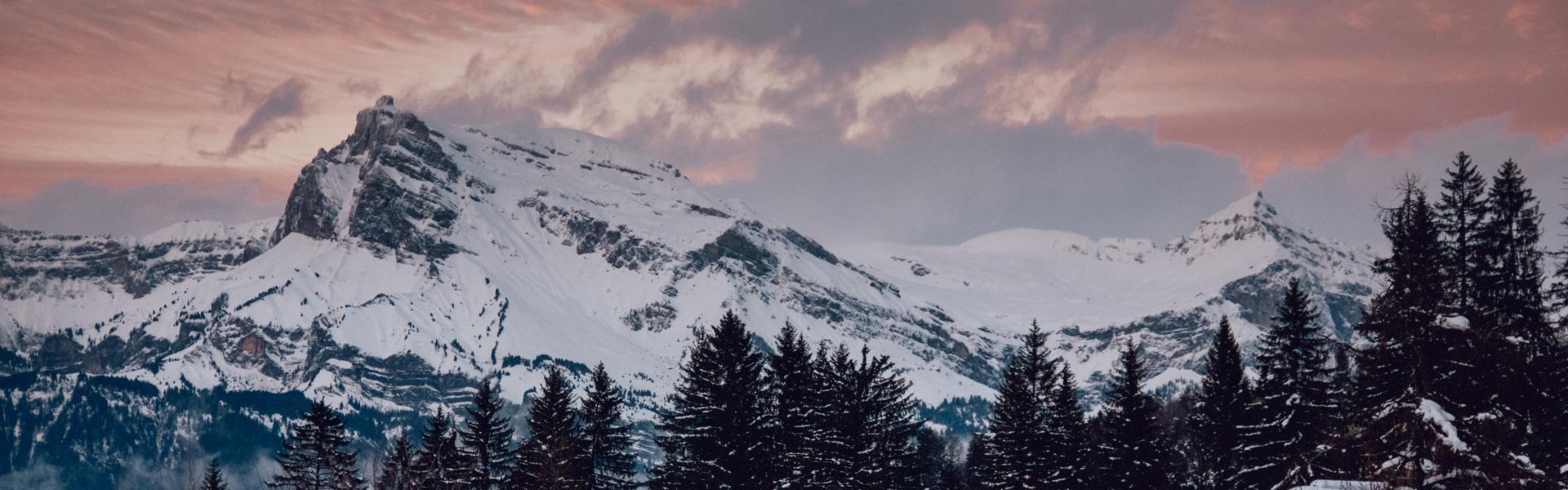 snow capped rocky mountain under cloudy sky during golden hour