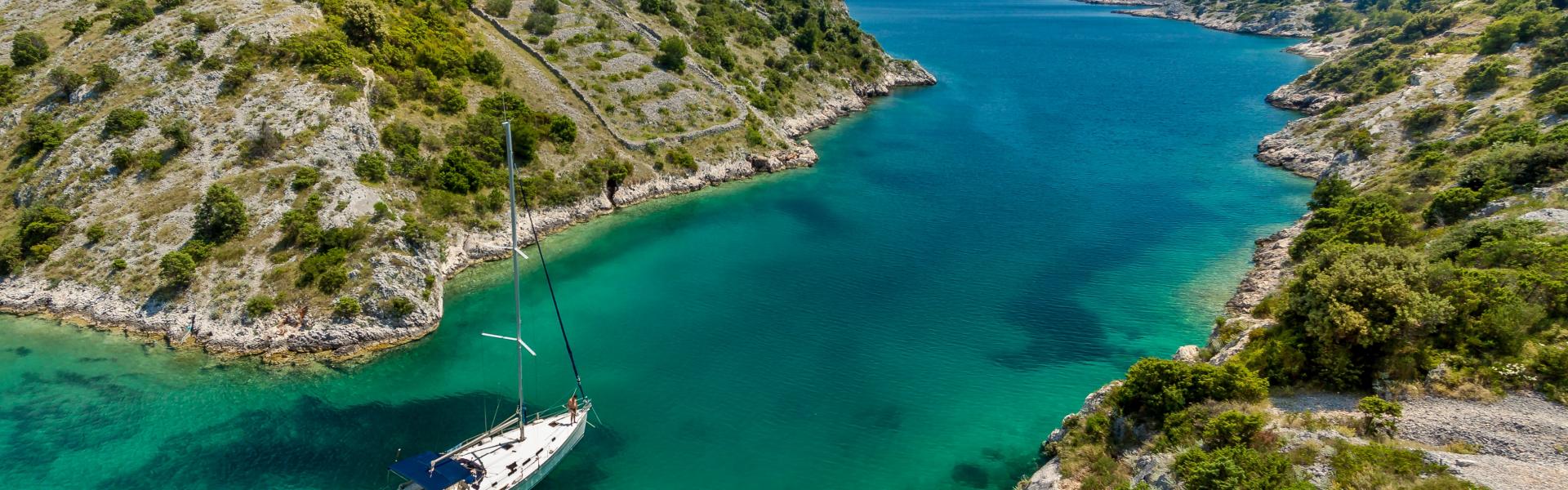 aerial photography of white boat near body of water between green mountain during daytime