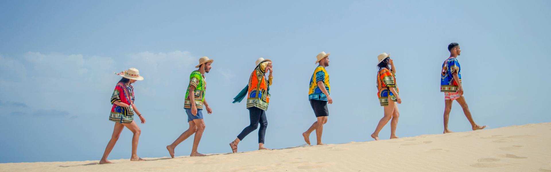 group of 6 people running on brown sand during daytime
