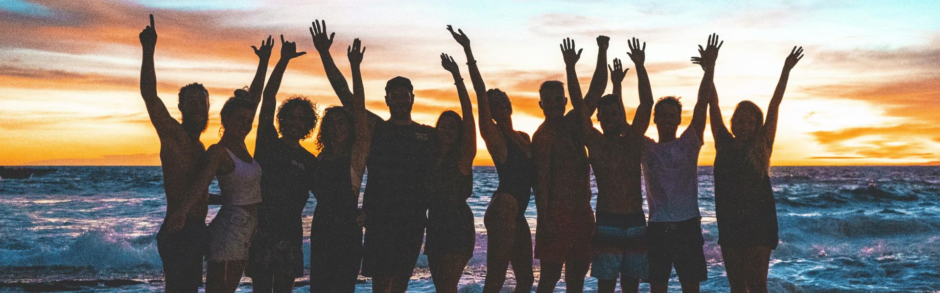 people raising arms on beach