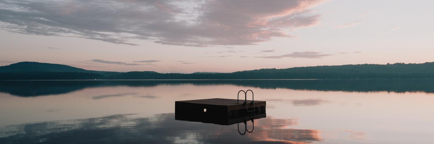 brown wooden bench on body of water under cloudy sky during daytime