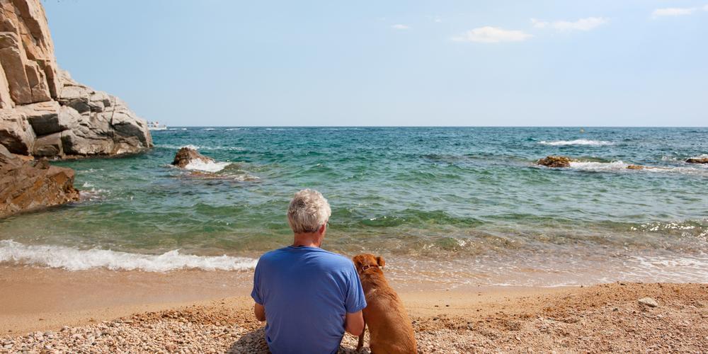 Man met hond op het strand in Spanje