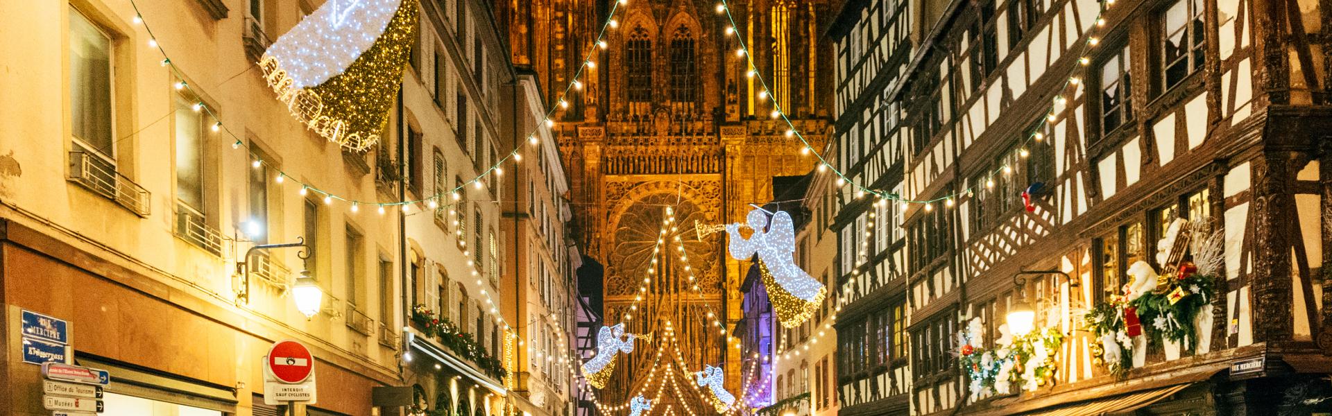 Tourists admiring Christmas decorations on the iconic rue Merciere and the Notre-Dame Cathedral