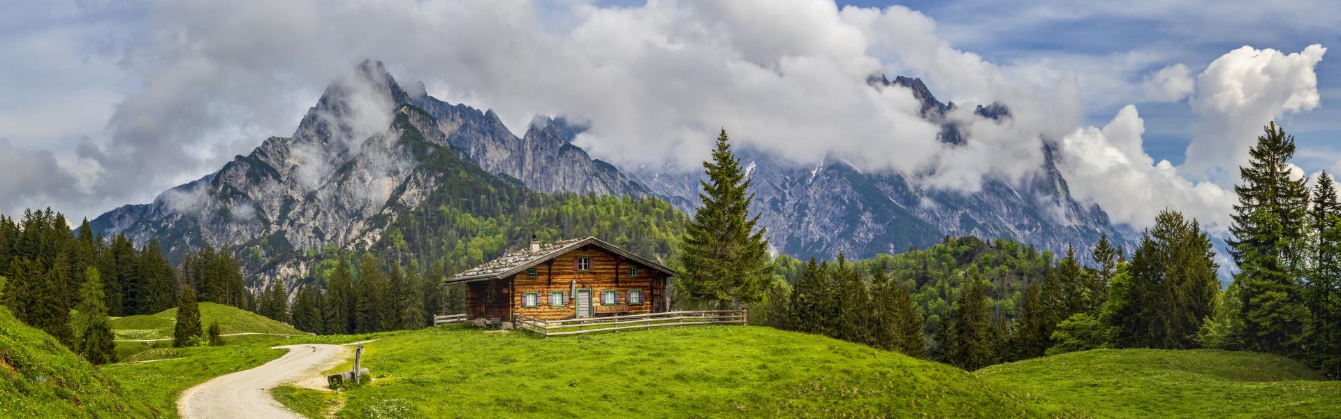 Beautiful view of scenic mountain landscape in the Alps with traditional mountain chalet and fresh green meadows