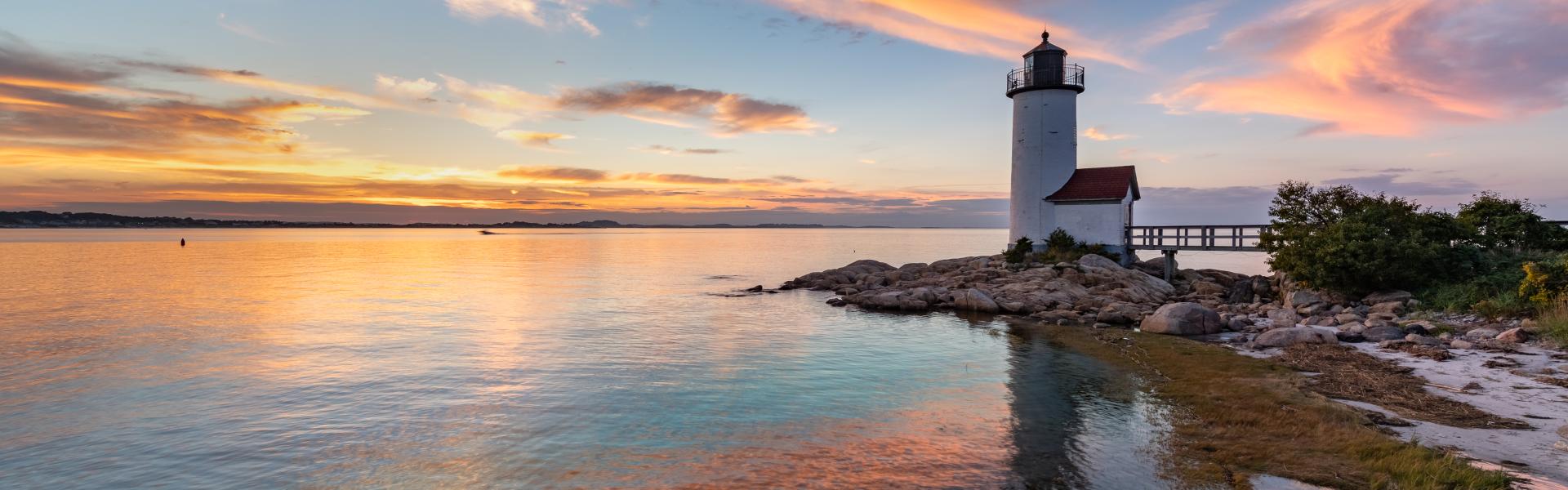 A lighthouse on a rocky outcrop at sunset